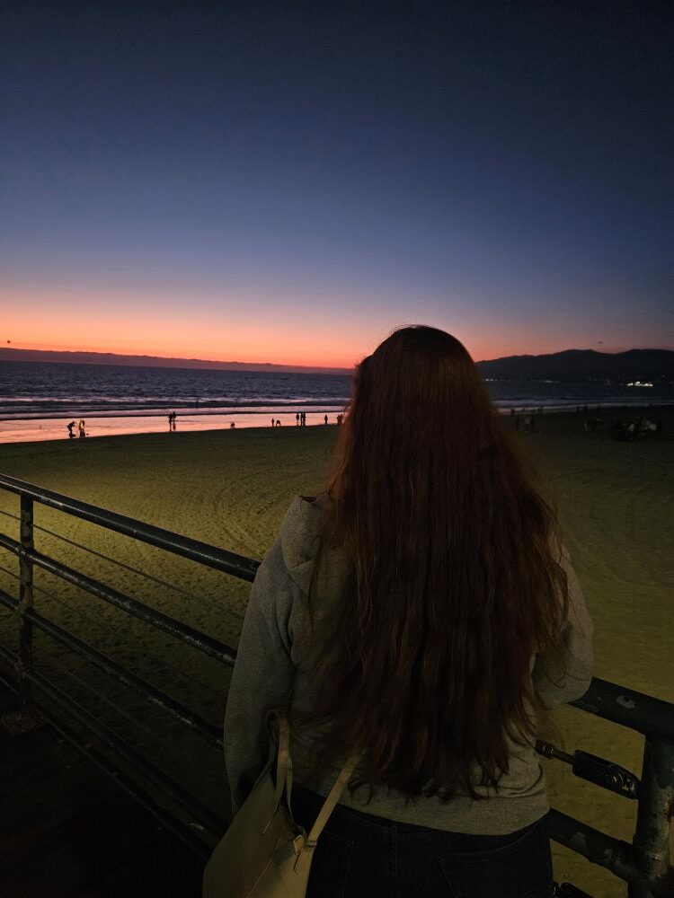 Fernanda observando o pôr do sol no píer de Santa Monica durante nosso roteiro de 6 dias em Los Angeles.